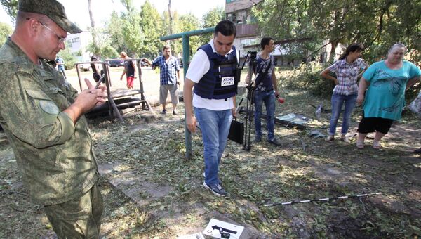 Представители Специальной мониторинговой миссии (СММ) ОБСЕ осматривают воронку от снаряда во время фиксации разрушений в Ясиноватой в Донбассе в результате обстрела города со стороны украинских силовиков