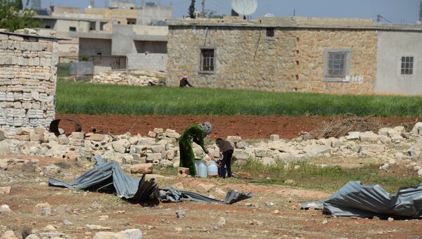Жители одного из населенных пунктов у дороги из Алеппо в Хомс набирают в емкости воду. Архивное фото