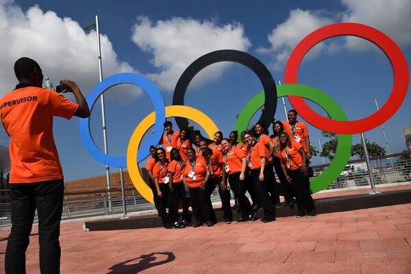 Волонтеры фотографируются у олимпийских колец в Олимпийском парке в Рио-де-Жанейро, Бразилия
