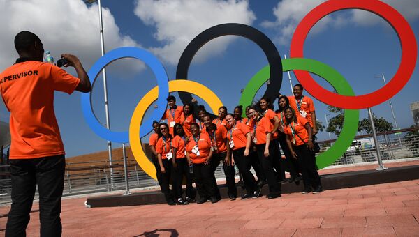 Волонтеры фотографируются у олимпийских колец в Олимпийском парке в Рио-де-Жанейро. Архивное фото