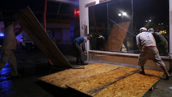Жители заколачивают окна магазина в Мексике из-за приближения урагана Эрл