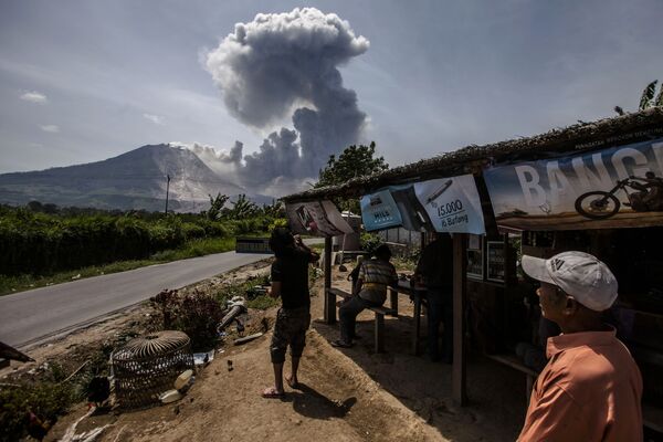 Индонезийские жители смотрят на вулкан Синабунг