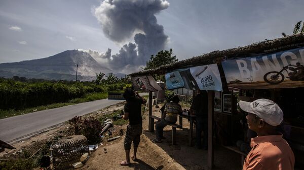 Индонезийские жители смотрят на извержение вулкана Синабунг