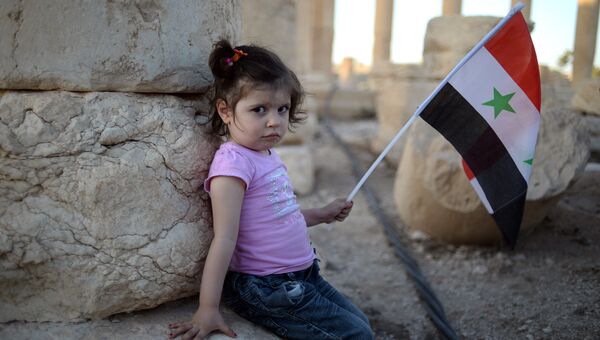 Девочка с сирийским флагом в исторической части Пальмиры