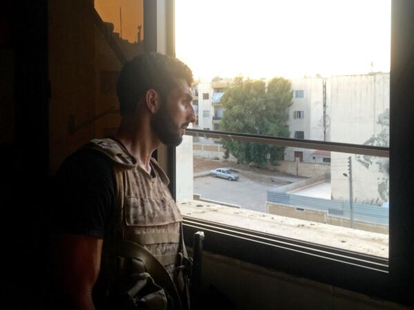 Боец сирийской армии осматривает позицию из окна квартиры на юге города Алеппо в Сирии