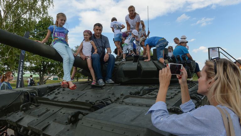 Посетители выставки фотографируются на танке Т-90 во время соревнований по танковому биатлону на полигоне Алабино