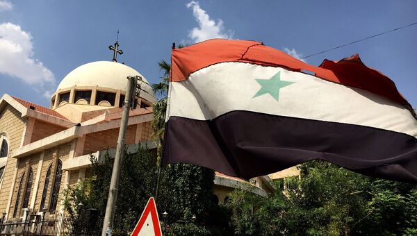 Сирийский флаг на фоне православной церкви в старом христианском квартале Алеппо. Архивное фото