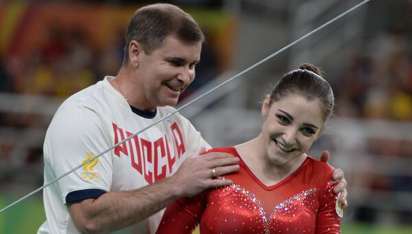 Алия Мустафина с тренером после окончания выполнения упражнений на разновысоких брусьях на XXXI летних Олимпийских играх