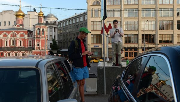 Молодые люди играют в Pokemon Go от компании Nintendo на экране мобильного телефона возле станции метро Китай город в Москве