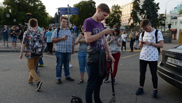 Молодые люди играют в Pokemon Go от компании Nintendo на экране мобильного телефона в Ильинском сквере в Москве. Архивное фото