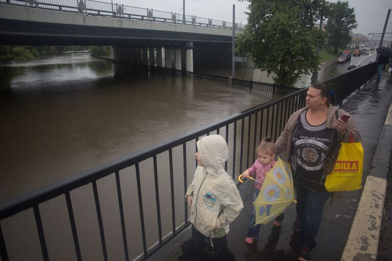 Женщина с детьми во время дождя у реки Яуза, где перекрыто автомобильное движение из-за разлива реки