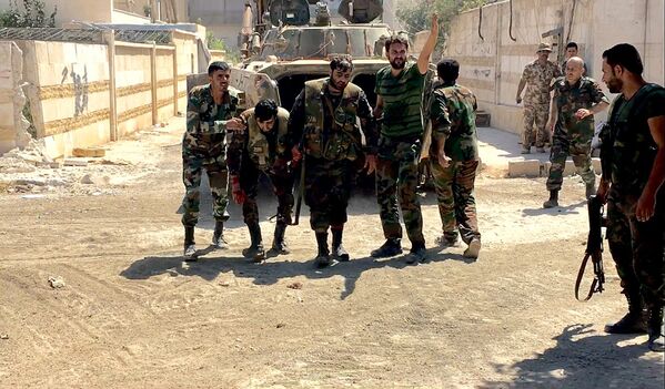 Бойцы сирийской армии выводят раненого при штурме военных училищ на юго-западе Алеппо