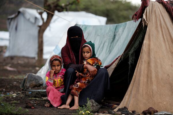 Женщина с детьми у палатки в лагере для беженцев неподалеку от Саны, Йемен. Август 2016