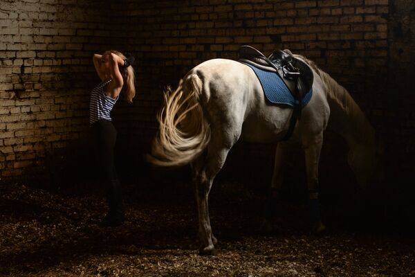 Спортсменка после тренировки со своей лошадью в конюшне Центра спортивной подготовки по конному спорту в Новосибирске