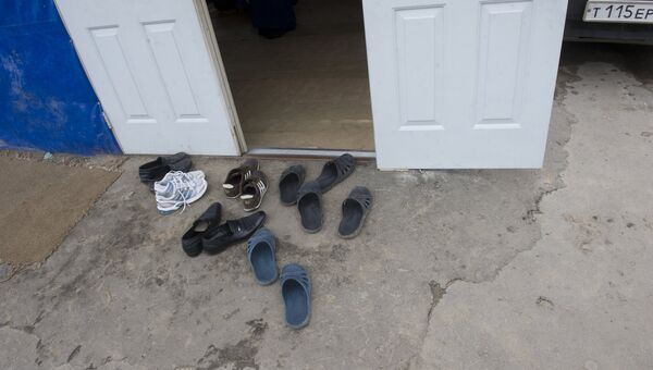 Обувь у двери вагончика где живут иностранные рабочие. Архивное фото