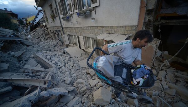 Мужчина с детской коляской в пострадавшем от землетрясения итальянском Аматриче. 24 августа 2016