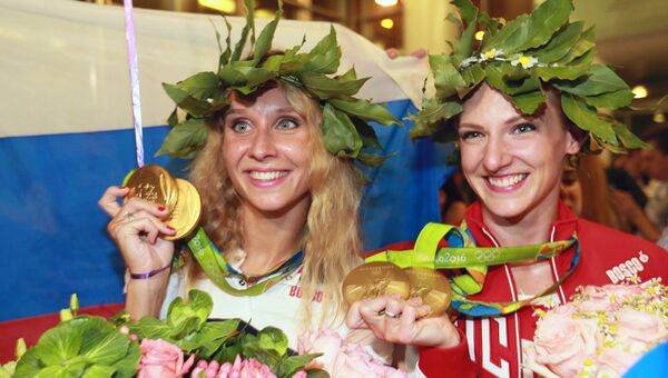Пятикратные олимпийские чемпионки Светлана Ромашина (справа) и Наталья Ищенко во время церемонии встречи в аэропорту Шереметьево. Архивное фото