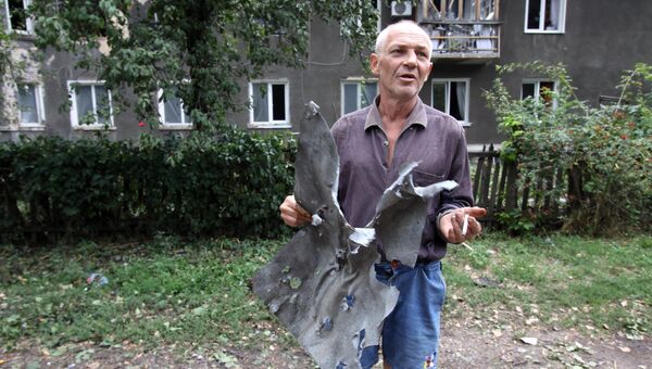 Житель Горловки показывает часть обшивки дома, которую сорвало во время взрыва снаряда. 25 августа 2016