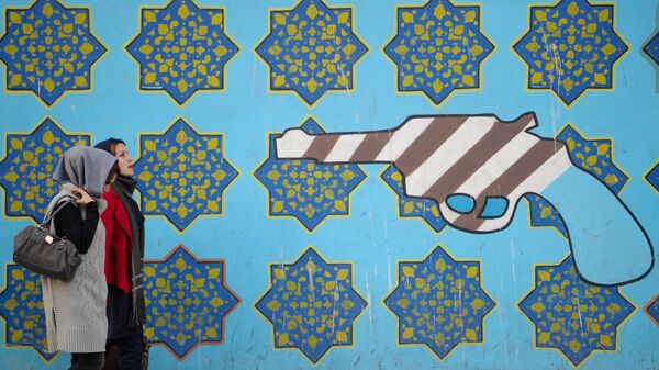 Женщины идут вдоль стены здания бывшего посольства США в Тегеране