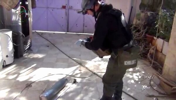 Эксперт из миссии ООН в Сирии обследует гильзу от снаряда в пригороде Дамаска