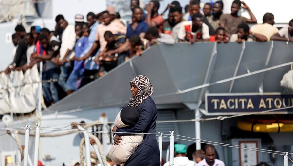 Женщина сходит с корабля ВМС Италии в гавани Поццалло в Италии. Август 2016