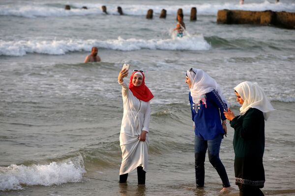 Женщина в хиджабе делает селфи на пляже в Тель-Авиве. Август 2016