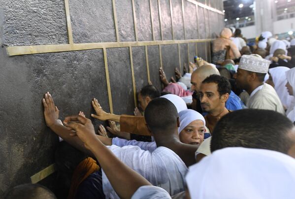 Паломники во время хаджа дотрагиваются до Каабы во время обхода вокруг нее в мечете Месжид аль-Харам в Мекке