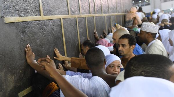 Паломники во время хаджа дотрагиваются до Каабы во время обхода вокруг нее в мечети Месжид аль-Харам в Мекке