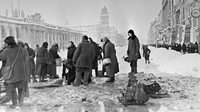 Жители блокадного Ленинграда набирают воду, появившуюся после артобстрела в пробоинах в асфальте. Архивное фото