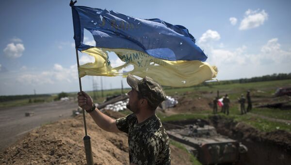 Украинский военный устанавливает флаг Украины в Марьинке недалеко от Донецка. Архивное фото