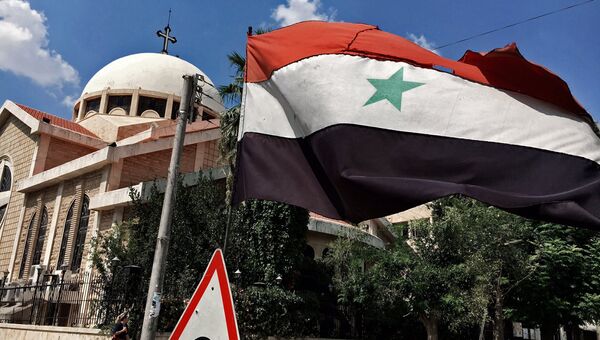 Государственный флаг Сирийской Арабской Республики у православной церкви в старом христианском квартале сирийского города Алеппо