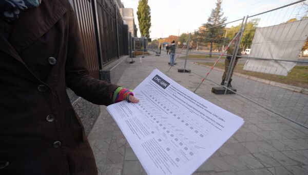 Женщина демонстрирует памятку для наблюдателя на выборах у посольства Российской Федерации в Киеве
