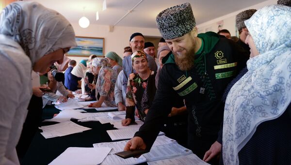 Временно исполняющий обязанности главы Чечни Рамзан Кадыров (второй справа) в единый день голосования на избирательном участке №165 в селе Центарой