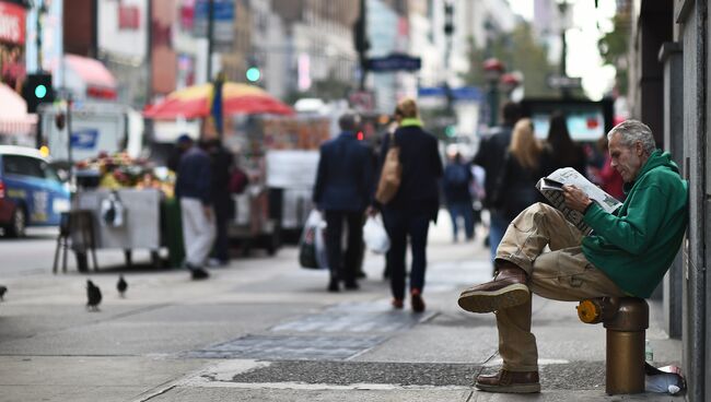 Мужчина читает газету на улице в Нью-Йорке, США. Архивное фото
