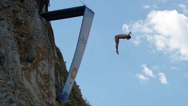 Спортсмен выполняет прыжок на тренировочной базе для занятия хай-дайвингом на скале Дива в Симеизе в Крыму