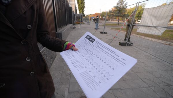 Женщина демонстрирует памятку для наблюдателя на выборах у посольства Российской Федерации в Киеве, где проходят выборы в единый день голосования. 18 сентября 2016