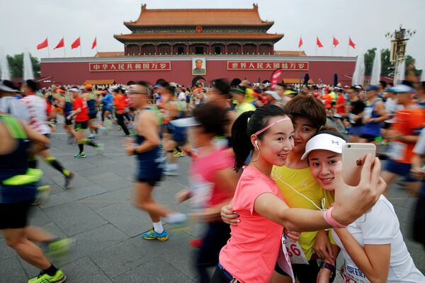 Девушки фотографируются во время ежегодного Пекинского марафона