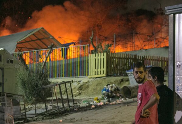 Мигранты наблюдают за пожаром в лагере для беженцев на острове Лесбос
