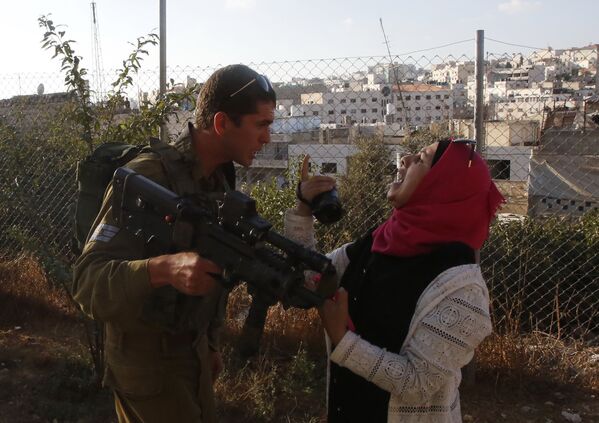 Израильский солдат отбирает камеру у палестинской женщины в городе Хеврон, Израиль