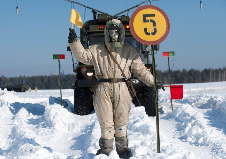 Военнослужащий в противогазе стоит возле контрольно-распределительного подвижного пункта во время тактико-специальных занятий подразделений радиационной, химической и биологической защиты ЦВО