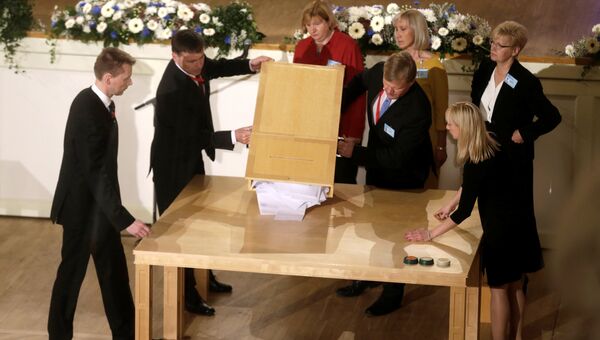 Члены избирательной комиссии опустошают ящик для голосования во время президентских выборов в Таллинне, Эстония, 24 сентября