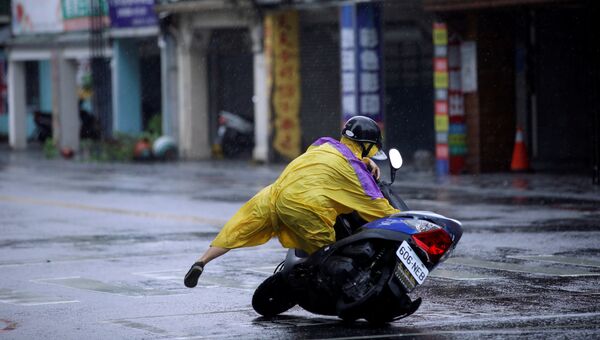 Мужчина с мопедом на улице города Хуалянь во время тайфуна Меги на Тайване. 27 сентября 2016