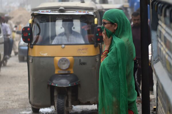 Женщина закрывает лицо, чтобы защитить себя от загрязненного воздуха в Пакистане