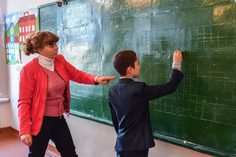 Учитель начальных классов Оксана Русакова и Дима (9 лет) на уроке в школе села Сенное в Брянской области Учитель начальных классов Оксана Русакова и Дима (9 лет) на уроке в школе села Сенное в Брянской области