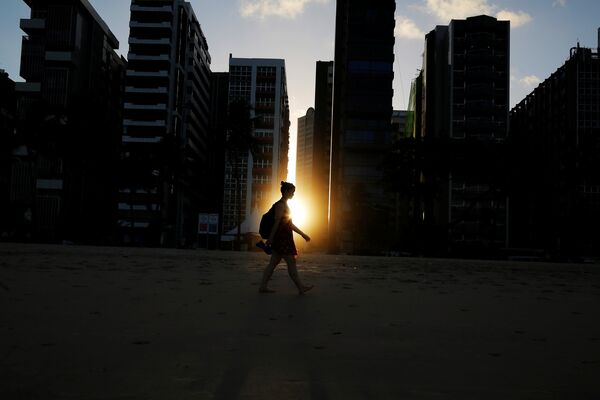 Девушка идет по пляжу на закате в Бразилии