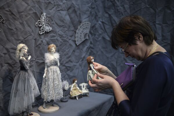Посетительница рассматривает куклу на 12-й международной выставке-ярмарке Салон авторской куклы в Москве
