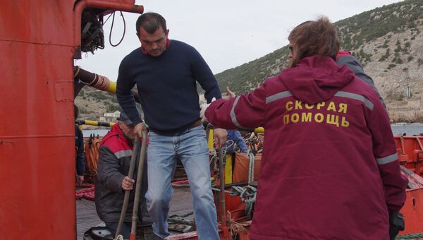 Сотрудница скорой помощи встречает одного из спасенных членов экипажа плавучего крана, затонувшего у берегов Крыма, в порту Балаклавы