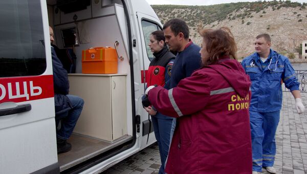 Сотрудники скорой помощи и один из спасенных членов экипажа плавучего крана, затонувшего у берегов Крыма, в порту Балаклавы