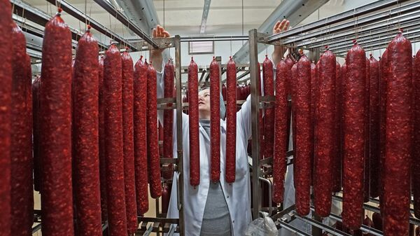 Сотрудник во время производства мясных деликатесов. Архивное фото