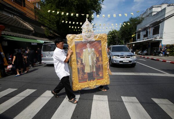 Люди с портретом короля Таиланда Пхумипона Адульядета на улице в Бангкоке